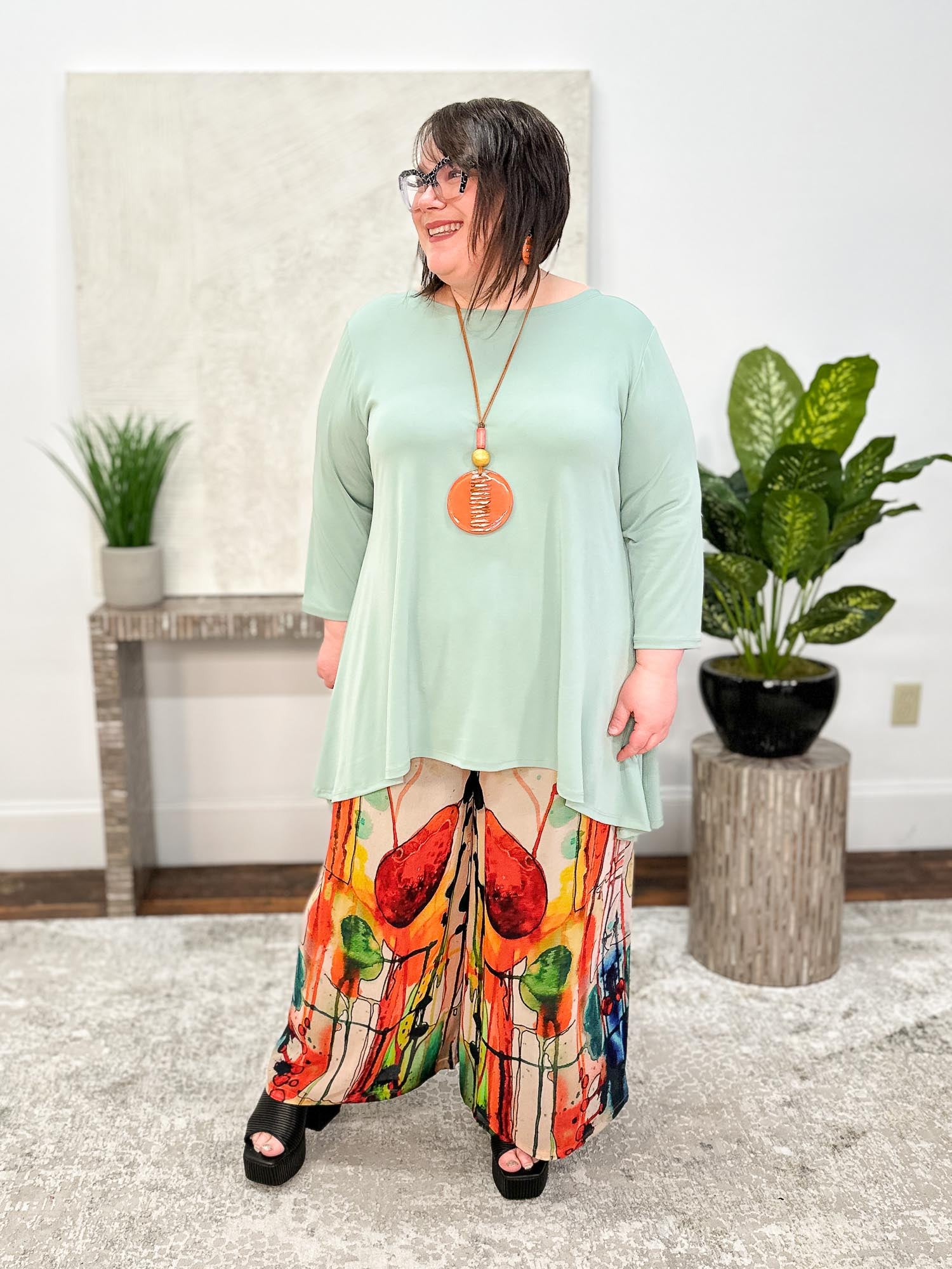 Andrea models Kozan's Dima Top, Sage Vogue with Sterling Styles' Palazzo Pant, Soho and International Duru's Round Pendant Necklace & Earrings Set, Orange